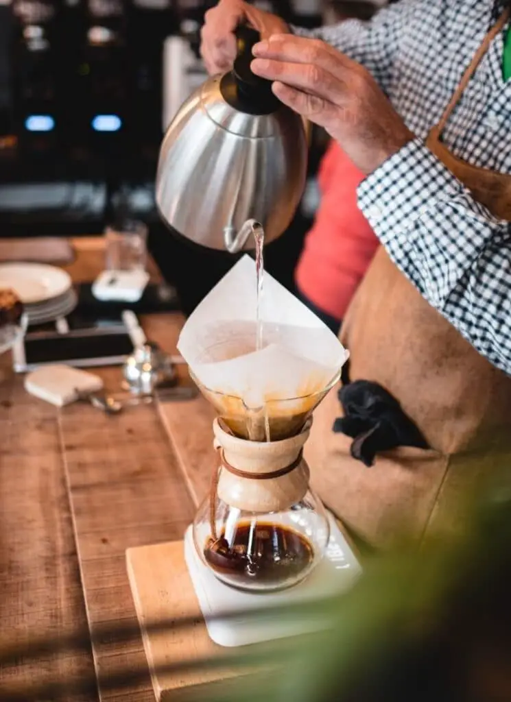 man pouring water into coffee filter with kettle underneath