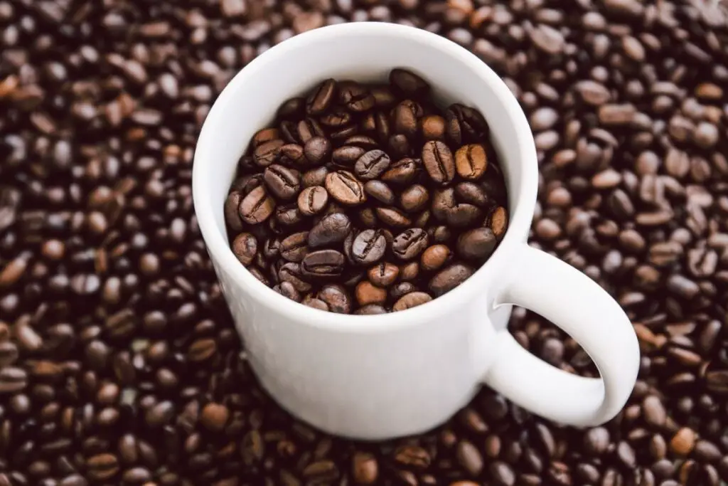coffee cup filled and surrounded by coffee beans