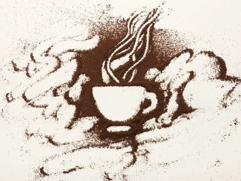 coffee cup design drawn with finger into spilled coffee grounds