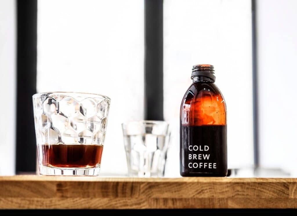 glass with coffee and cold brew bottle labeled cold brew