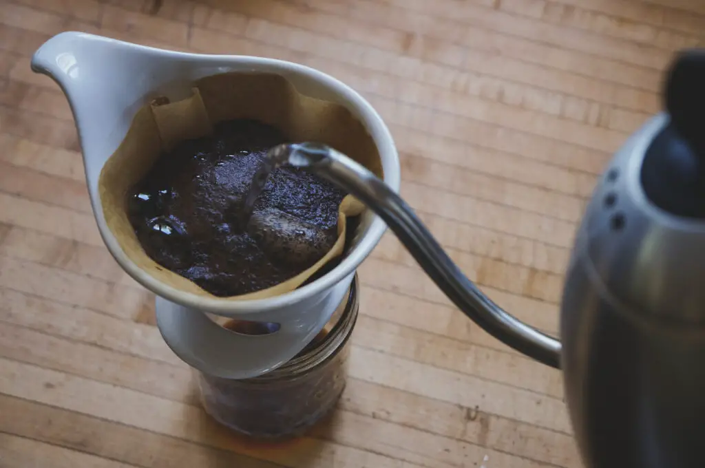 pouring water from kettle into pour over coffee maker