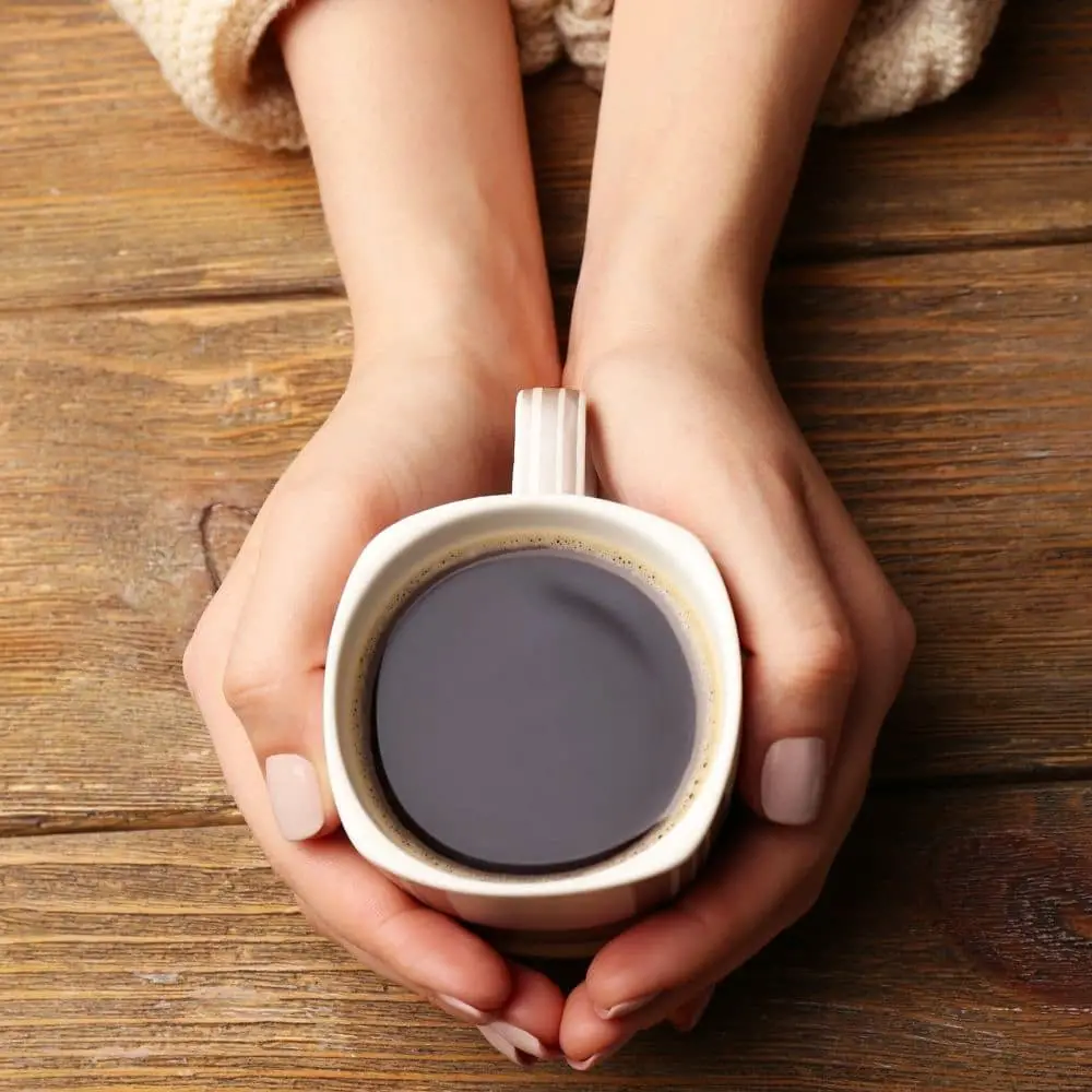 coffee in cup being held by womans hands