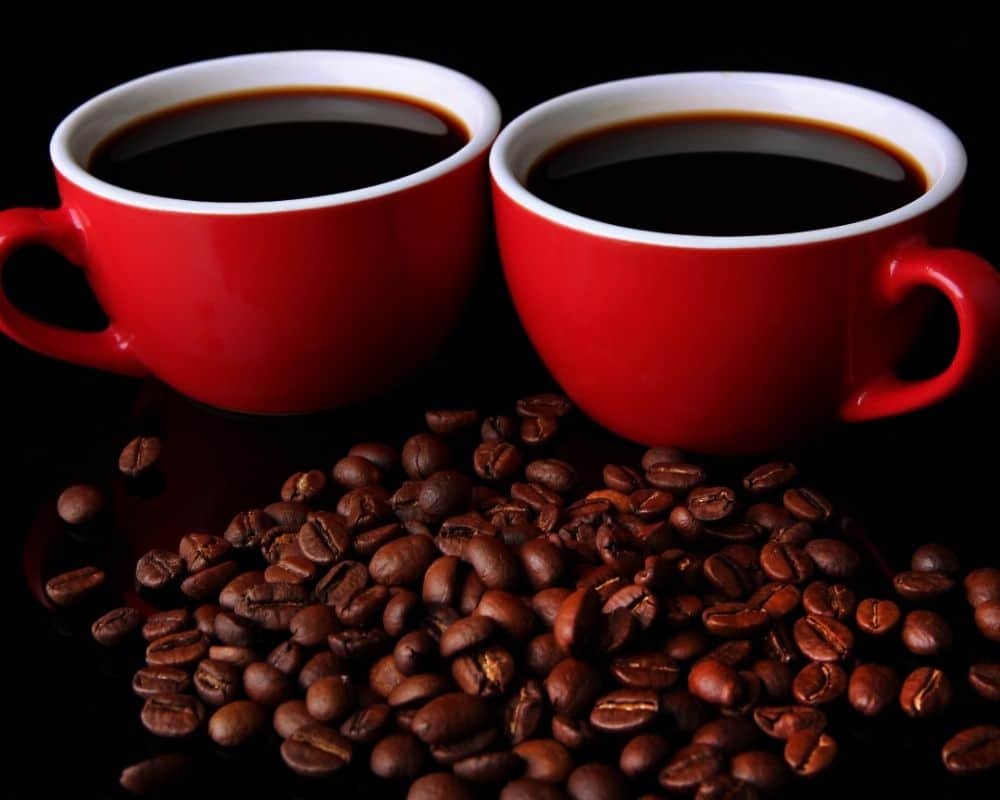 2 red coffee cups and coffee beans